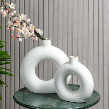 White ceramic donut vase set styled on a green marble table creating a modern artistic decor accent with soft curved shapes adding elegance to contemporary interiors.