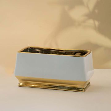 Elegant white and gold ceramic rectangular planter styled in a warm lifestyle setting adding a modern decorative accent to shelves tables and consoles.