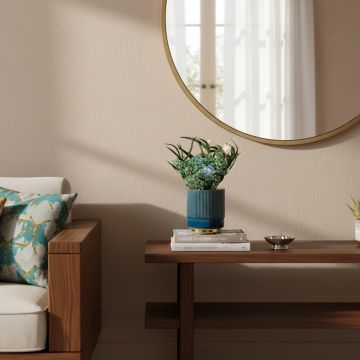 A blue ribbed ceramic vase with a glossy gold rim placed on a wooden console table beside decor elements creating a warm lifestyle setting with soft natural light.