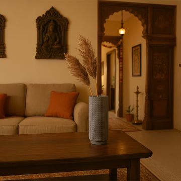 Grey ceramic vase with textured square pattern styled with dried pampas grass on a wooden coffee table in a warm living room setting.