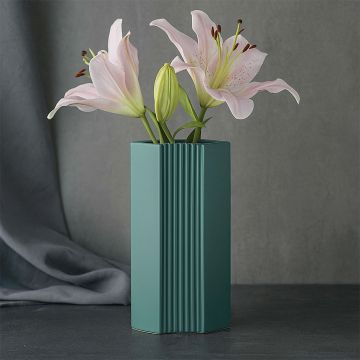 Ceramic flower vase in matte teal finish featuring vertical ribbed texture  holding fresh pink lilies against a dark modern backdrop.