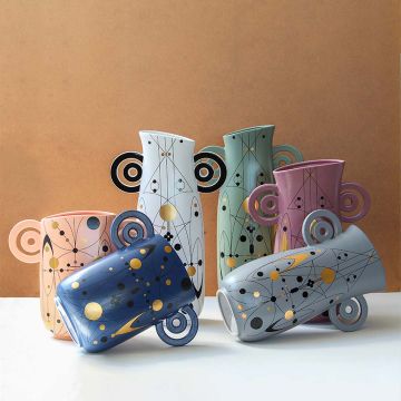 Grey abstract ceramic vase with artistic loop handles styled with matching decor pieces perfect for modern creative home interiors.