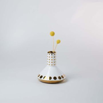 Elegant white and gold polka dot vase placed with flowers as a centerpiece in modern interiors.