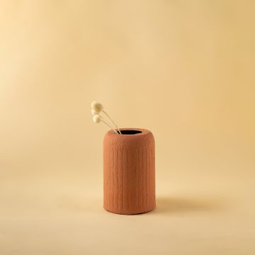 Terracotta ribbed ceramic vase placed in a soft minimal layout bringing warm natural tones to home styling.