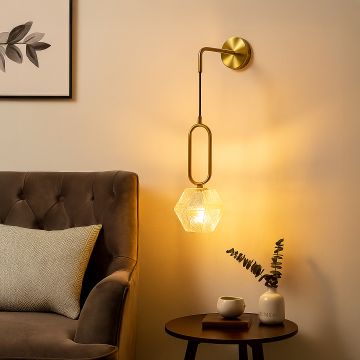 Gold and glass wall light illuminating a modern living space adding elegance and warm ambience to home interiors.