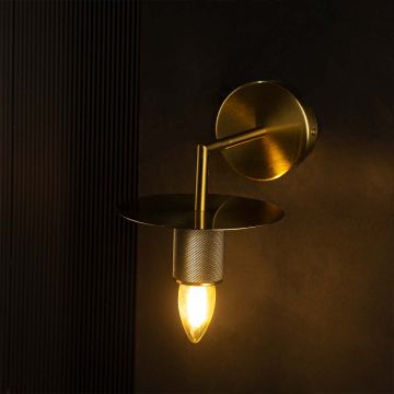 Gold metal wall light glowing warmly on black background highlighting its modern round shade and elegant finish.