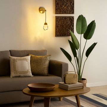 Gold crystal wall light glowing beside sofa in modern living room for elegant home interior wall lighting decor.
