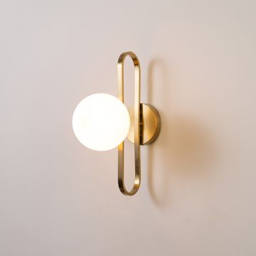 Wall sconce glowing with frosted white glass globe and gold metal frame perfect for bedroom living room and luxury interiors.