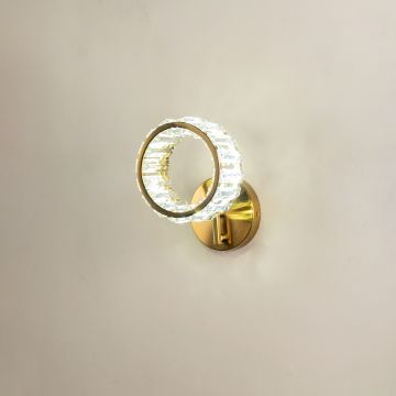 A modern circular wall light crafted from textured glass and gold metal glowing brightly against a clean white wall creating luxurious artistic contemporary décor.