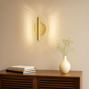 Gold metal wall light with clear acrylic decorative shade adding warm ambient lighting to a modern elegant interior.