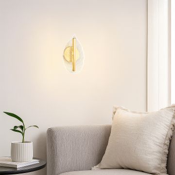 Gold metal and clear glass leaf wall light styled in a modern living room offering soft ambient decor accent lighting for home.