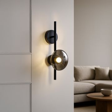 Black wall light with smoked textured glass shade adding warm ambient lighting to a modern stylish interior.