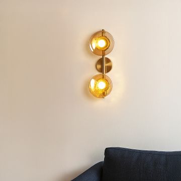 Gold double wall light with amber textured glass globes adding warm ambient lighting to a modern stylish interior.