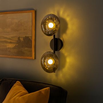 Stylish black metal wall sconce with dual smoked glass globes mounted on interior wall creating modern ambient lighting.