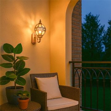 Gold metal outdoor wall lantern with warm light on creating a cozy glow on a balcony seating area for elegant exterior home lighting decor.