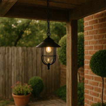 A warm outdoor pendant light glowing softly under a wooden pergola creating a cozy garden ambiance with brick walls and greenery around the space.