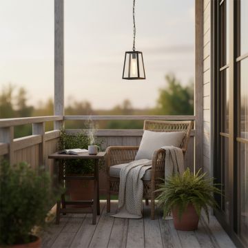 Warm glowing black metal outdoor hanging lantern lighting up a cozy wooden balcony seating area with greenery creating a relaxing evening ambiance for home decor.