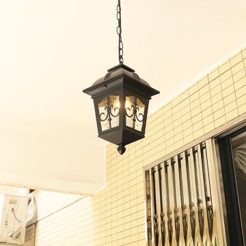 A decorative outdoor hanging lantern glowing warmly in a tiled entrance area enhancing the welcoming ambiance with its classic metal frame and illuminated panels.