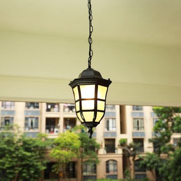 Black metal outdoor pendant light hanging on a balcony with warm light on creating a cozy ambience against a blurred building background.