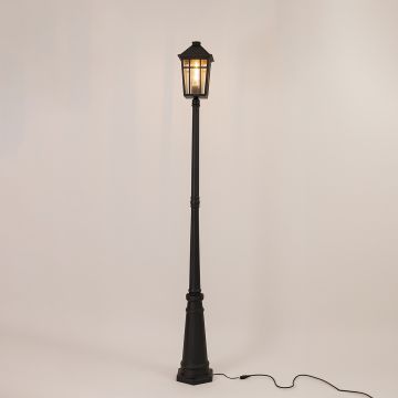 Illuminated black metal outdoor post lamp with glowing lantern head and clear glass panels on clean white background.
