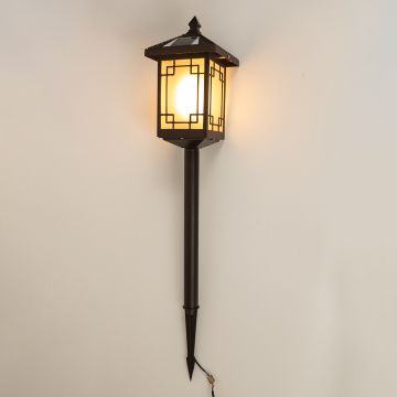 Brown solar garden spike lantern with frosted patterned glass shown with light on against a white background highlighting warm illumination and decorative design.