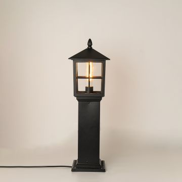 Black outdoor pillar lamp with clear glass shown with light off on a white background displaying its structured frame and elegant outdoor form.
