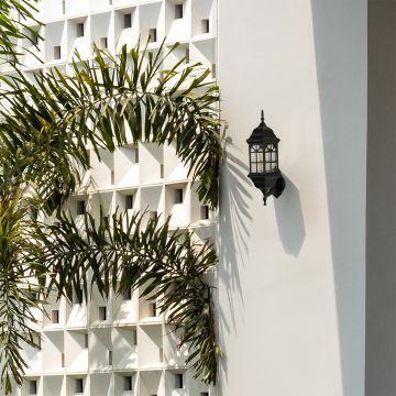 Black metal vintage outdoor lantern with arched window glass mounted on a white exterior wall creating a refined architectural lifestyle ambience.