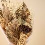Closeup of dried pampas grass bouquet with palm leaves ruscus preserved babysbreath and lotus pod creating a rustic floral arrangement.