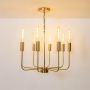 Illuminated brass gold metal eight light chandelier with vintage Edison filament tube bulbs glowing on curved arms background.