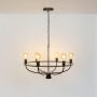 Illuminated black metal circular chandelier with six amber Edison globe bulbs glowing on cage frame against white background.