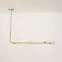 Gold linear chandelier with clear glass globes illuminated on a white background showing its modern design.