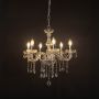 Crystal chandelier with lights on glowing warmly with elegant glass arms and crystal beads against black background.