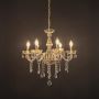 Crystal chandelier with gold frame and multiple candle lights glowing warmly on black background view.