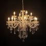 Elegant chandelier with crystal and gold accents illuminated against black background for stylish luxury lighting.