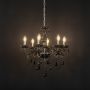 Elegant black chandelier with crystal accents illuminated against black background for luxury home decor.