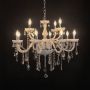Elegant white chandelier with crystal accents illuminated against black background for luxury interior lighting.