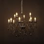 Elegant black chandelier with glossy arms and crystal droplets illuminated against black background decor.