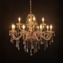 Golden chandelier with crystal detailing illuminated on black background for luxury home and hotel lighting.
