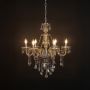 Golden chandelier with ornate crystal accents illuminated on black background for luxury decorative lighting.