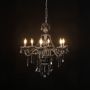 Chandelier illuminated with warm lights against a black background highlighting crystal design.