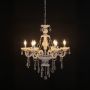 Chandelier with lights turned on featuring crystal details and warm glow on black background for modern interiors.