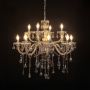 Chandelier with lights on featuring crystal chains and warm glow photographed against a black background.