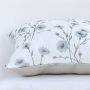 Closeup of the cushion showing detailed blue floral embroidery on a soft white fabric surface.