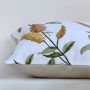 Closeup of the cushion showing detailed embroidered yellow and brown florals on soft white fabric.