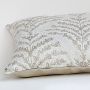Closeup view of the beige cushion showing detailed leafy embroidery and textured fabric surface.