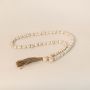 Minimalist photo of white bead garland on white background showing handcrafted details and neutral tones.