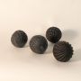 Single black carved decorative ball displayed on white background showcasing handmade textured surface and artisan craftsmanship.