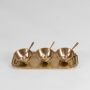 Three brass snack bowls with matching spoons arranged on a brass tray shown on a white background highlighting the full set and its refined detailing.
