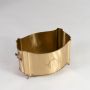 A gold metal storage basket with ornate detailing and curved edges shown on a white background highlighting its smooth finish and elegant craftsmanship.