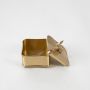 Square gold metal trinket box with a rabbit figurine handle on the lid standing closed against a clean white background for organization.